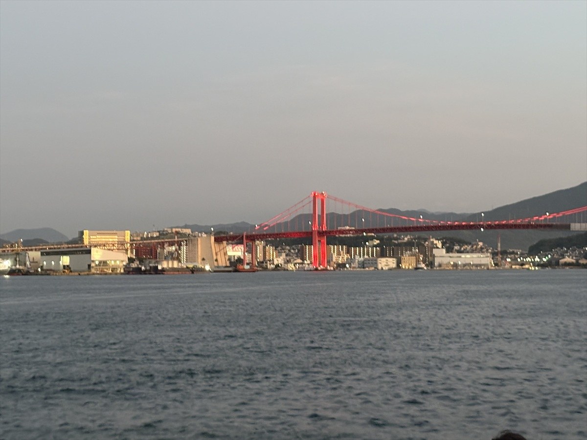 夕暮れの海上から遠くに見える赤い若戸大橋