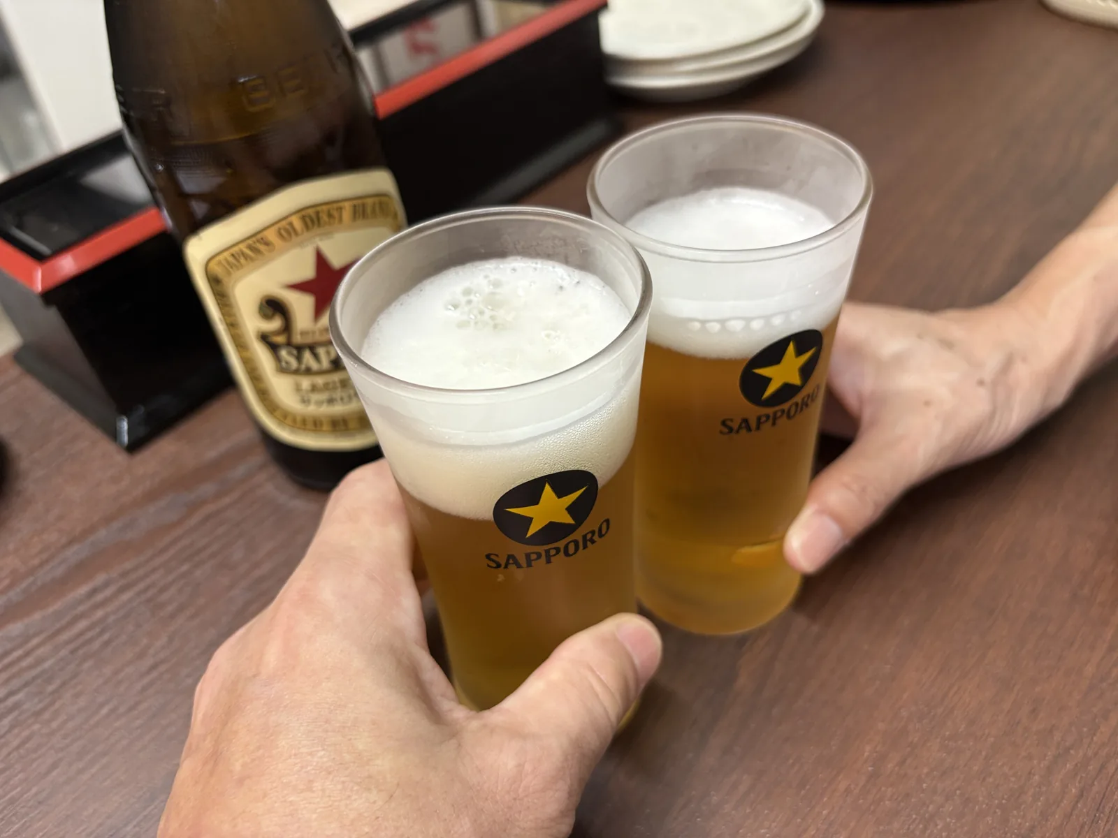赤星(サッポロラガービール)の瓶を横に、サッポロのロゴ入りグラス2つで乾杯
