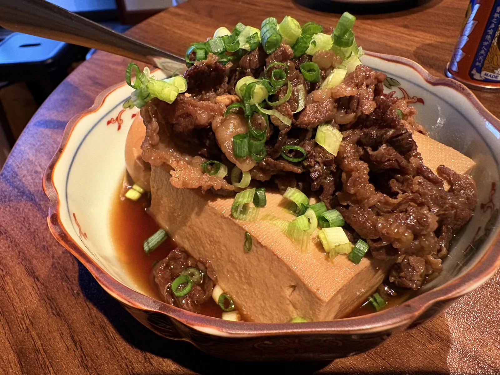 大きな豆腐の上に甘辛く煮た黒毛和牛がどっさり。刻みネギを散らし、器の底にはつゆ