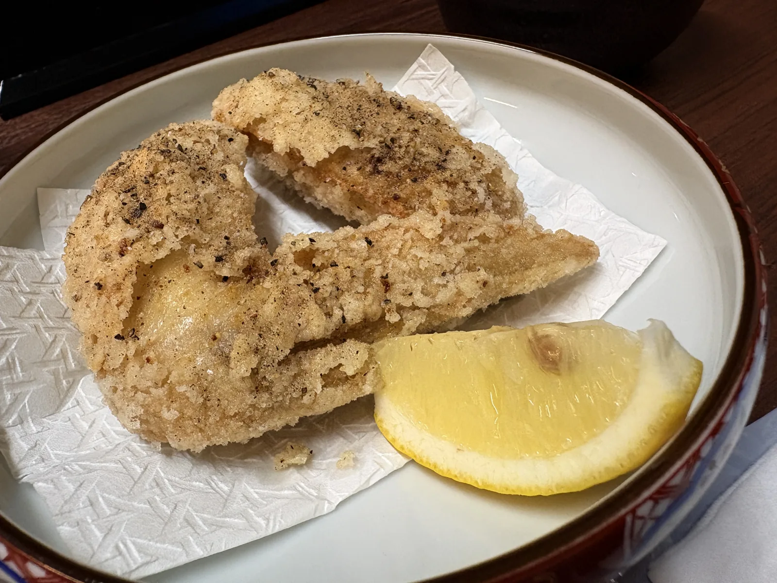 手羽先の唐揚げ2ピース。衣に黒こしょうが効いていて、レモン添え