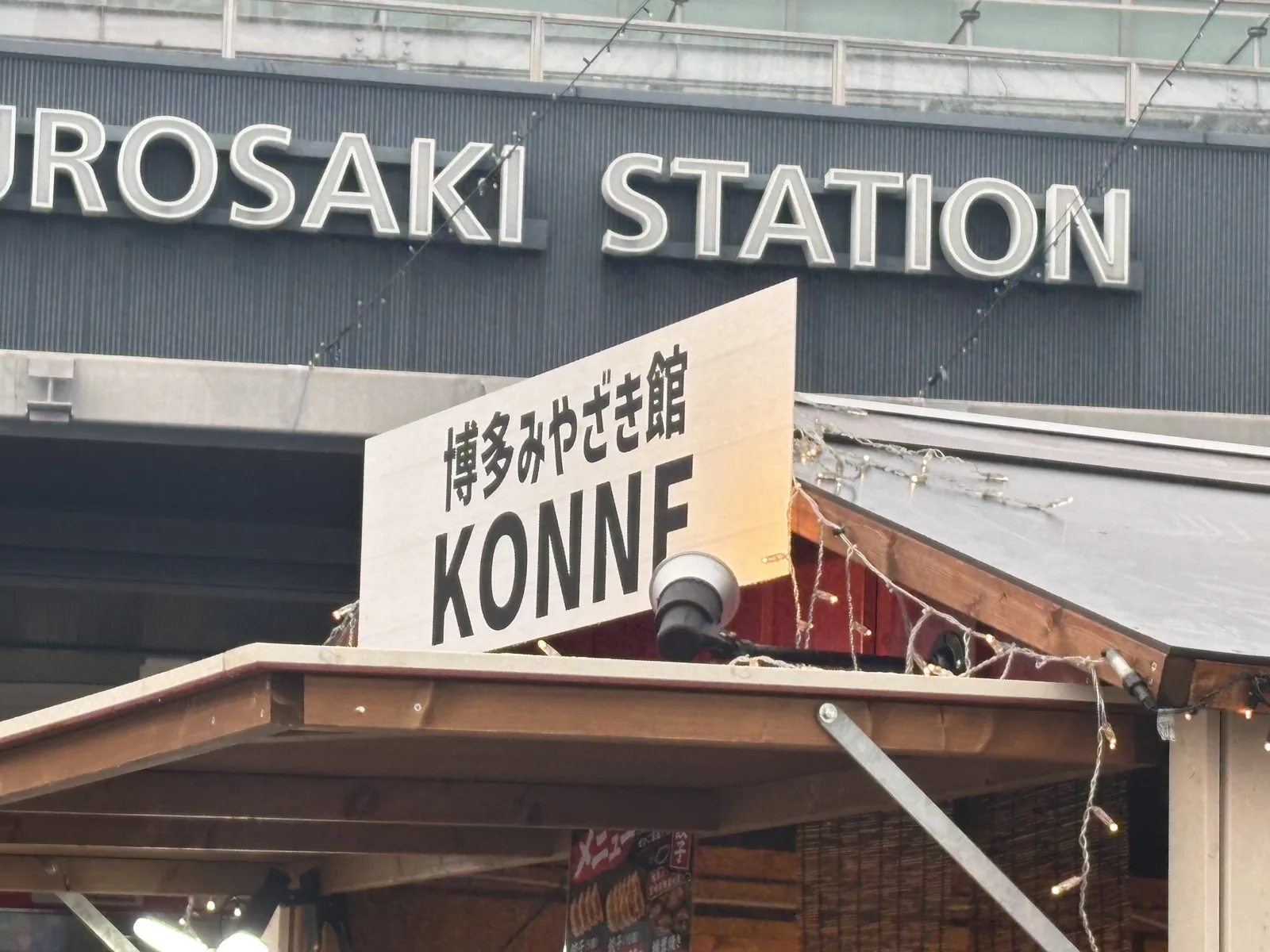 JR黒崎駅の駅名看板を背に立つ「博多みやざき館KONNE」の屋台