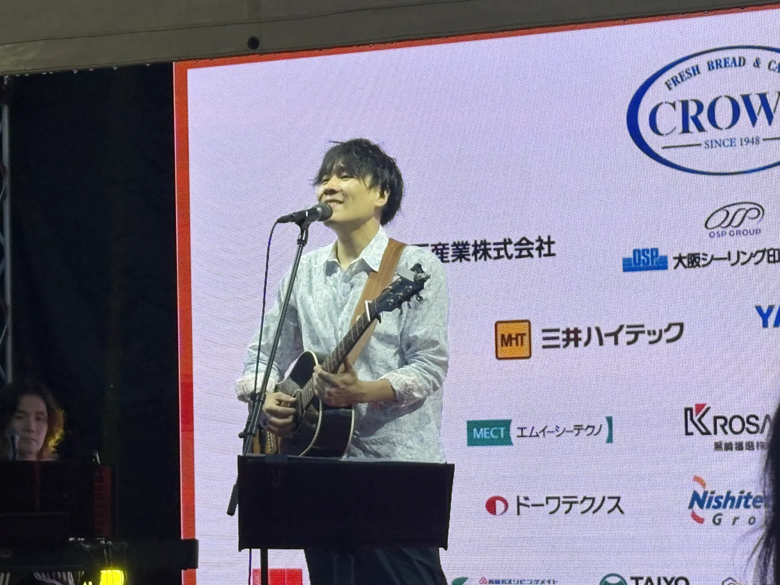 ステージでアコースティックギターを弾きながら歌う立川翼さん