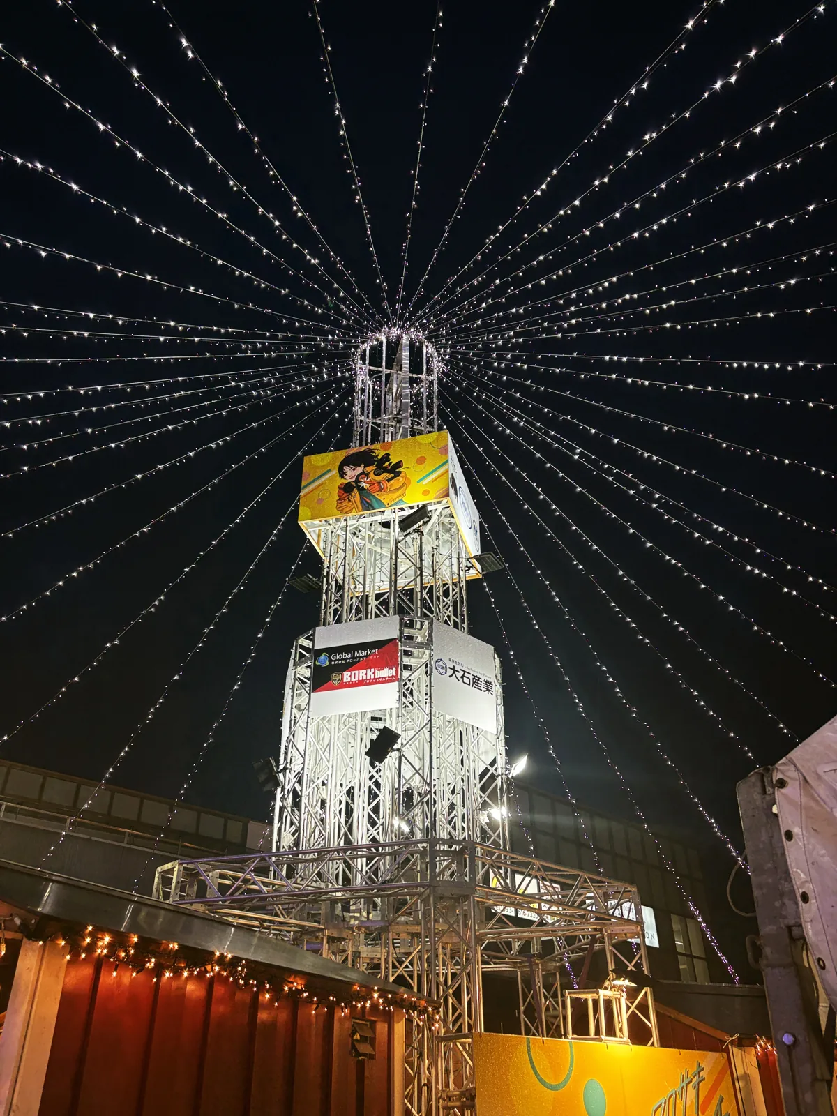 夜空に伸びるイルミネーションのタワーを真下から見上げる