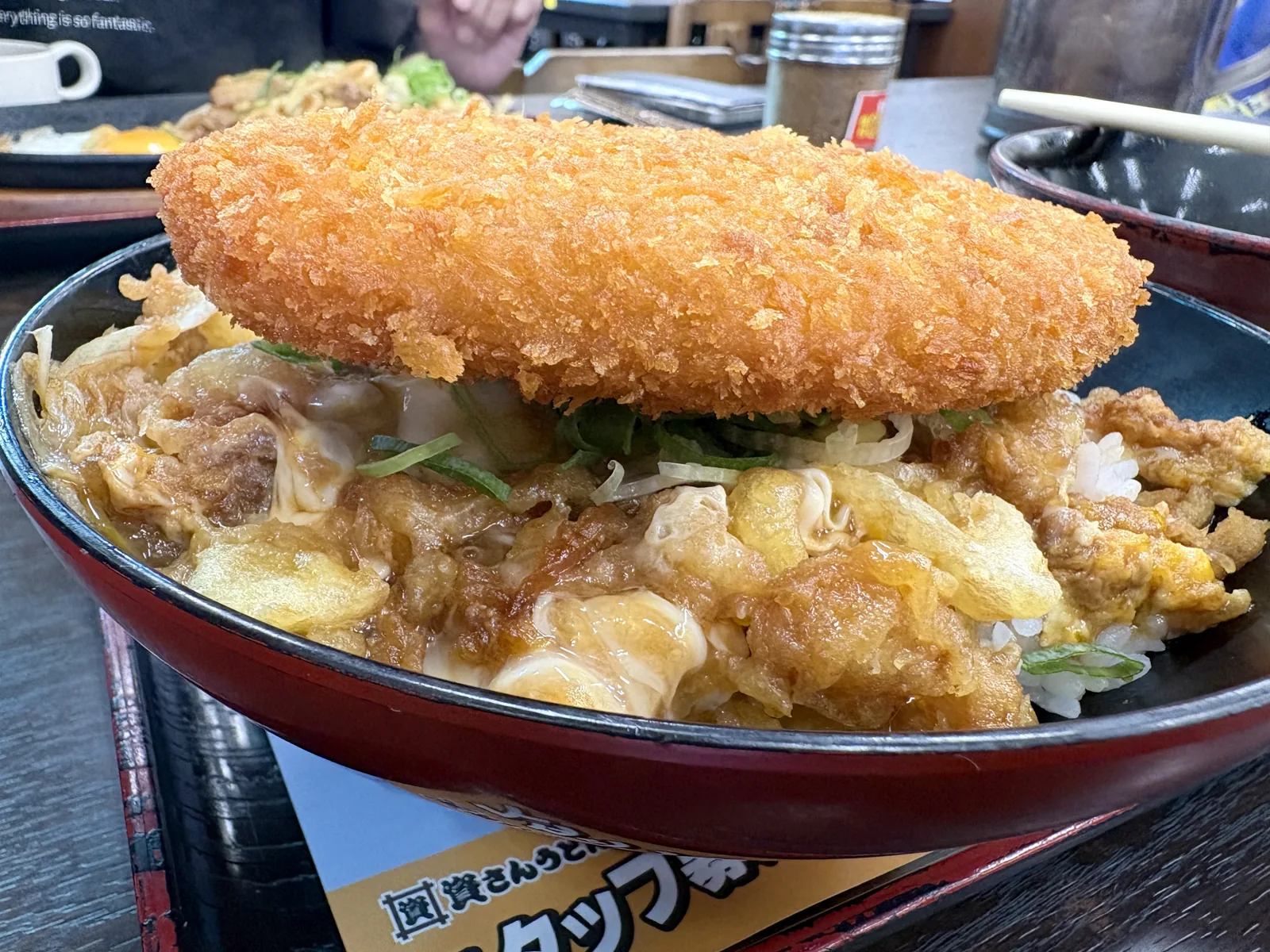 コロッケ丼を真横から。資たま丼の上にコロッケが分厚く乗っている