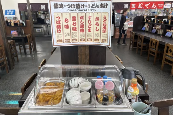 陣山店の店内中央に置かれた薬味コーナー。つぼ漬けや小皿、調味料がワゴンに並ぶ