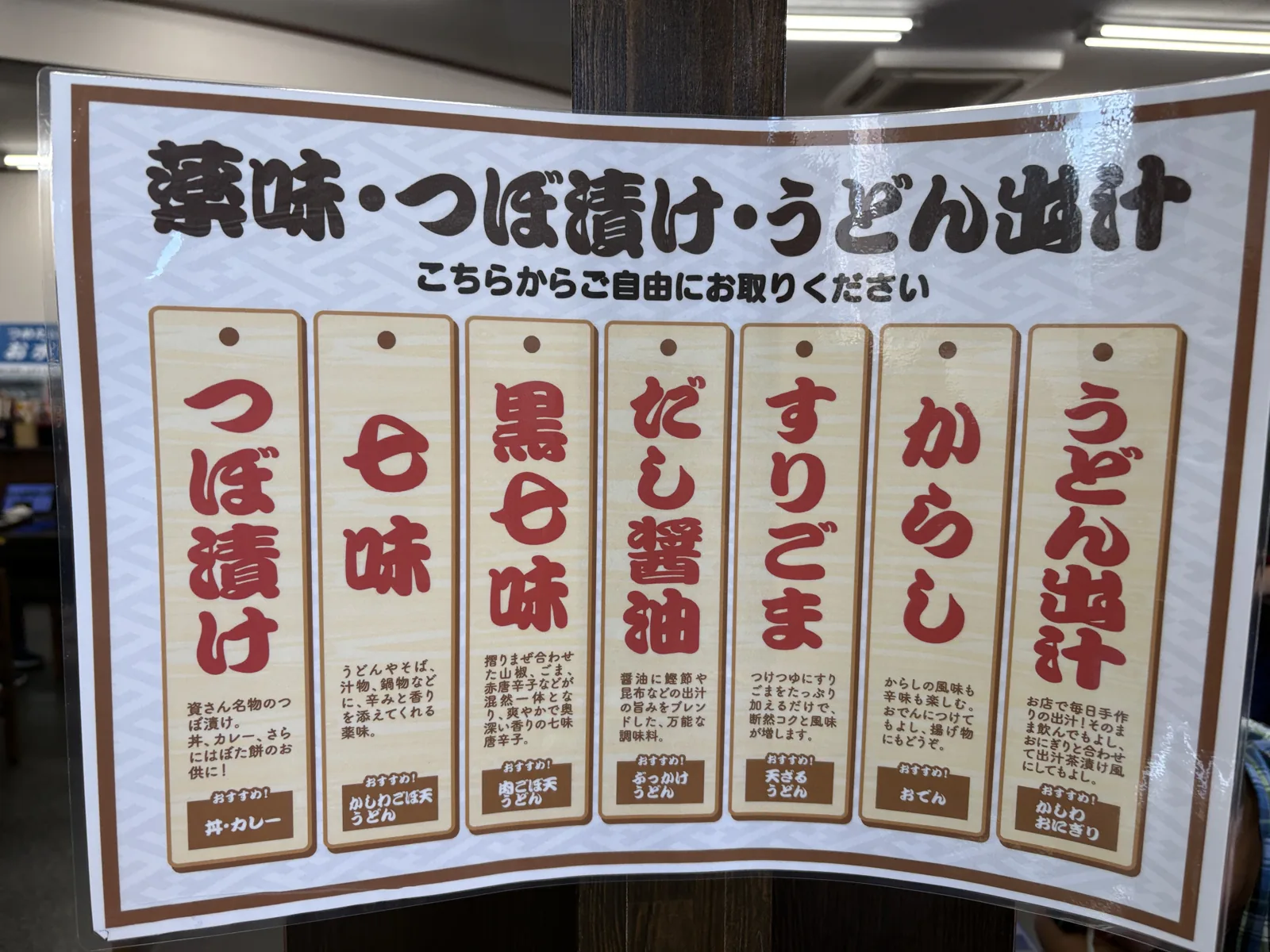 「薬味・つぼ漬け・うどん出汁 こちらからご自由にお取りください」の看板。7種類の薬味が札で紹介されている