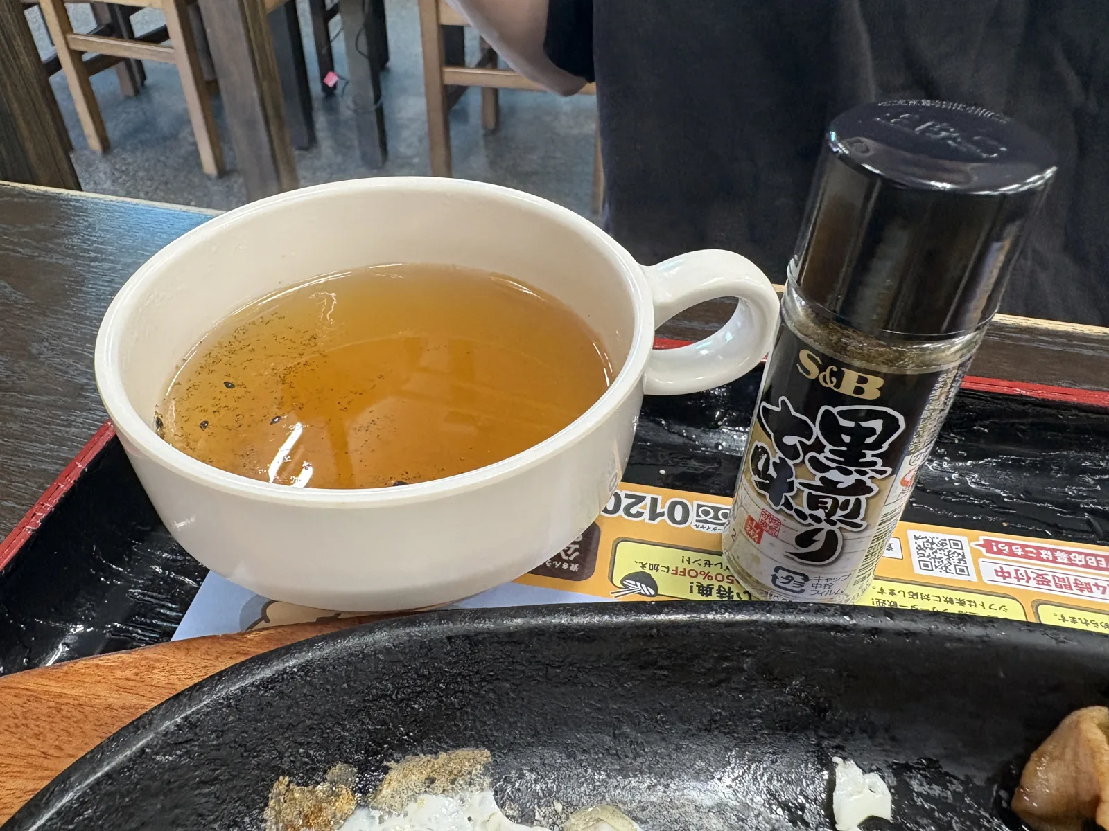 黒七味を振った出汁のカップと、S&Bの「黒煎り七味」のボトル