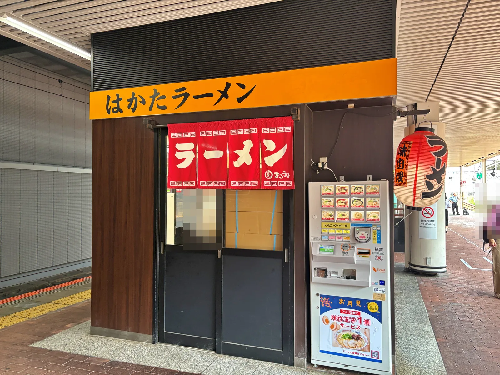 正面から。のれんの右に券売機。券売機の下に「アプリ登録で味付玉子1個サービス」のポスター