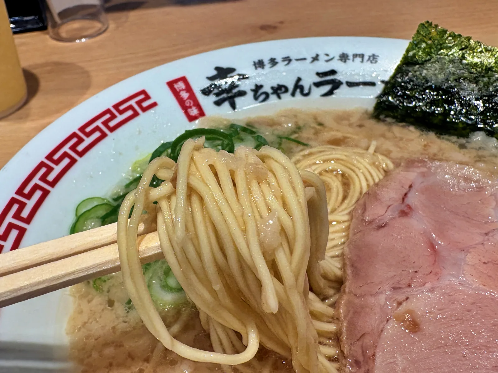 箸で持ち上げた細麺。背脂が絡んでいる
