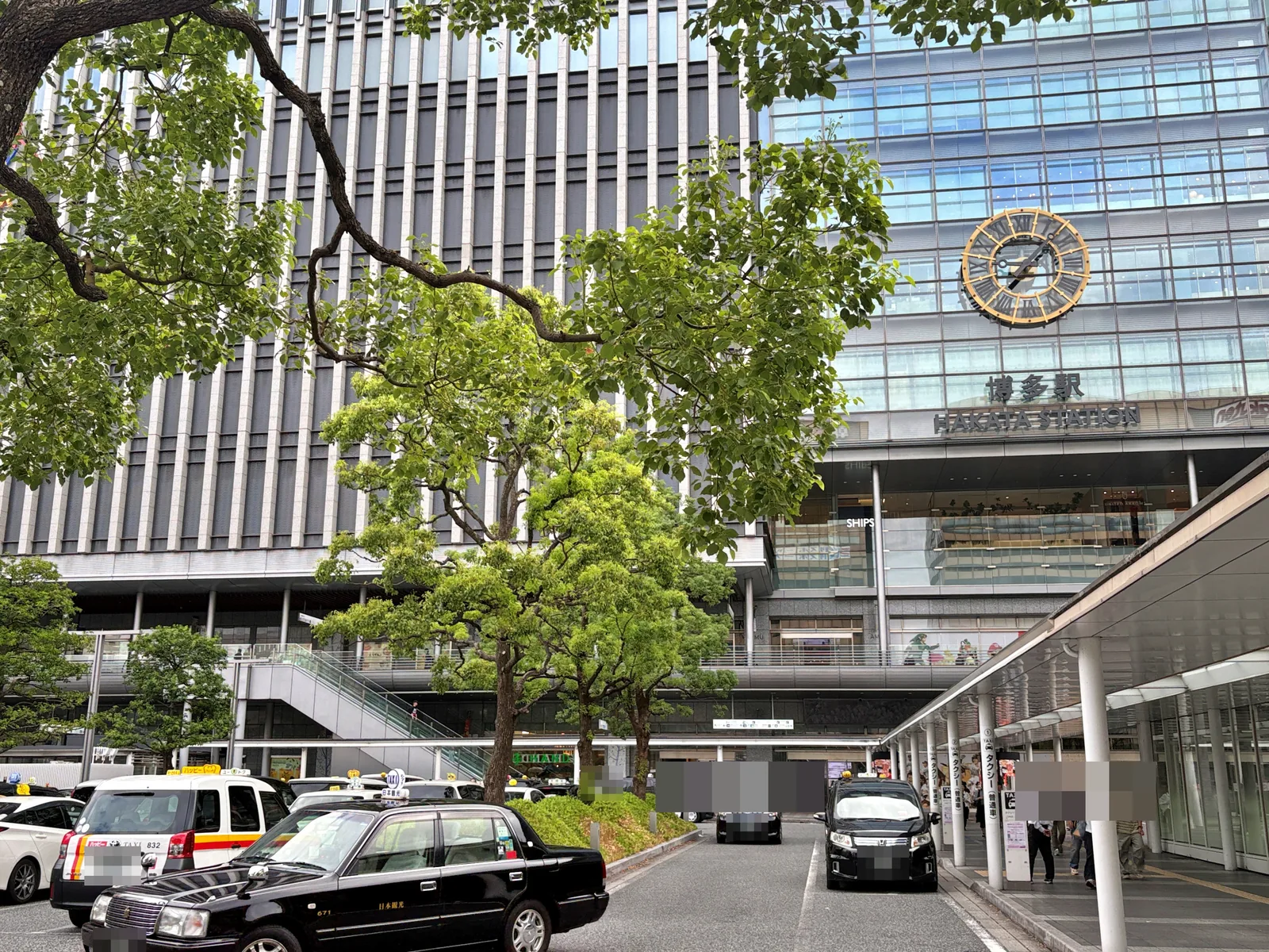 博多駅の駅舎。大時計と「博多駅 HAKATA STATION」の文字、手前にタクシー乗り場と街路樹