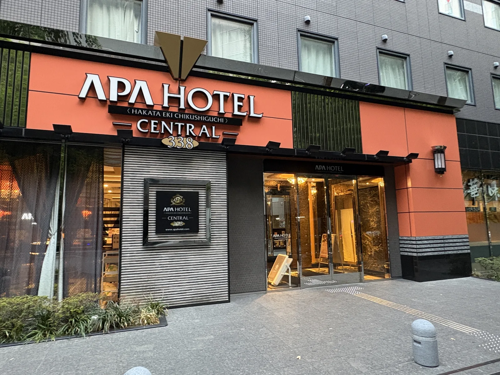 アパホテル〈博多駅筑紫口〉セントラル。オレンジの外壁に「APA HOTEL」の文字