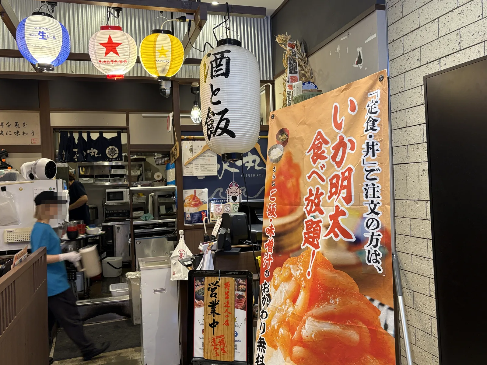 どんぶり喜水丸の店頭。提灯「酒と飯」と、のぼり「『定食・丼』ご注文の方は、いか明太食べ放題!」