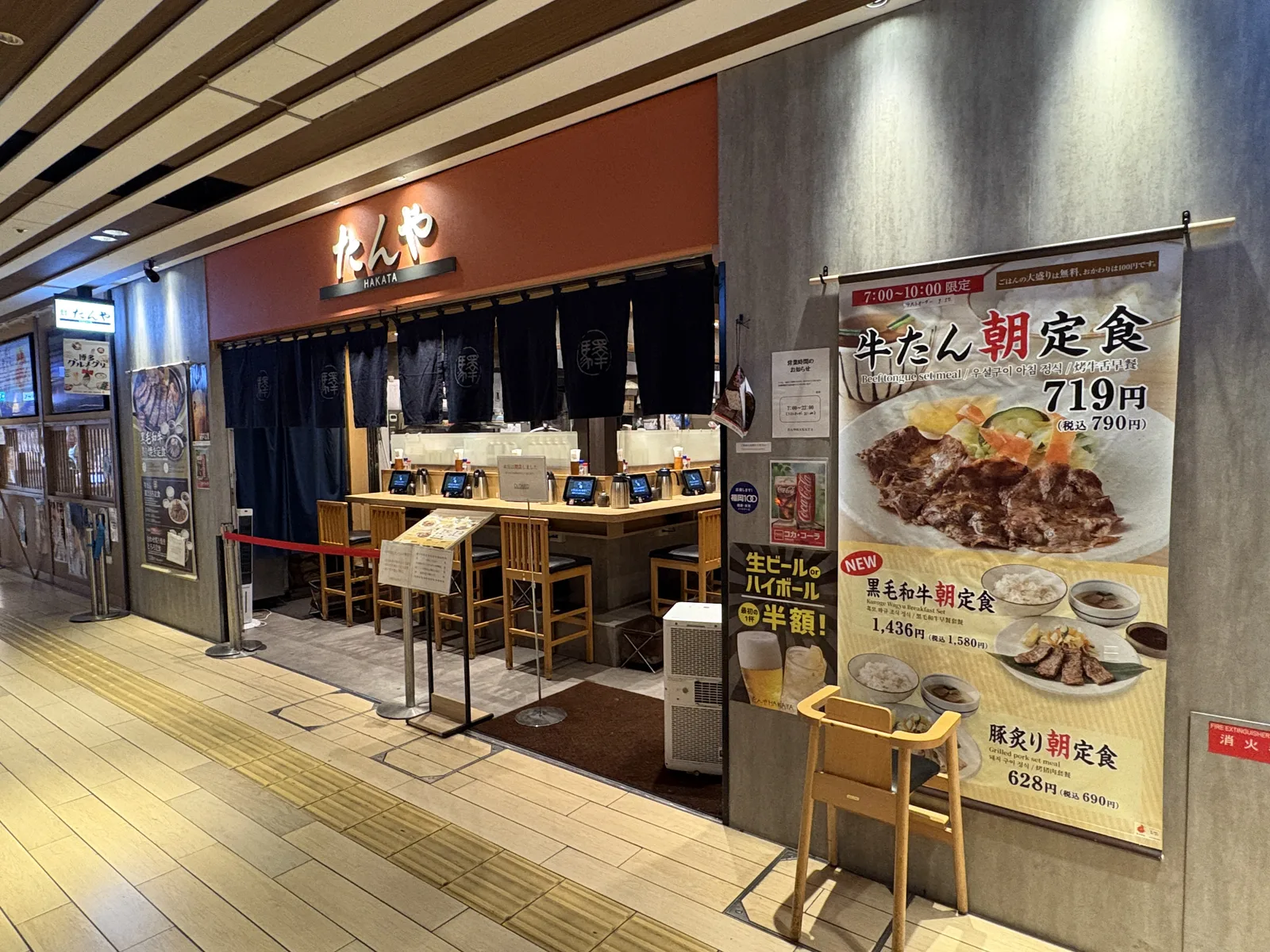 たんや HAKATA(6:59)。紺ののれんとカウンター席、右に「牛たん朝定食 719円(税込790円)」の大きなタペストリー