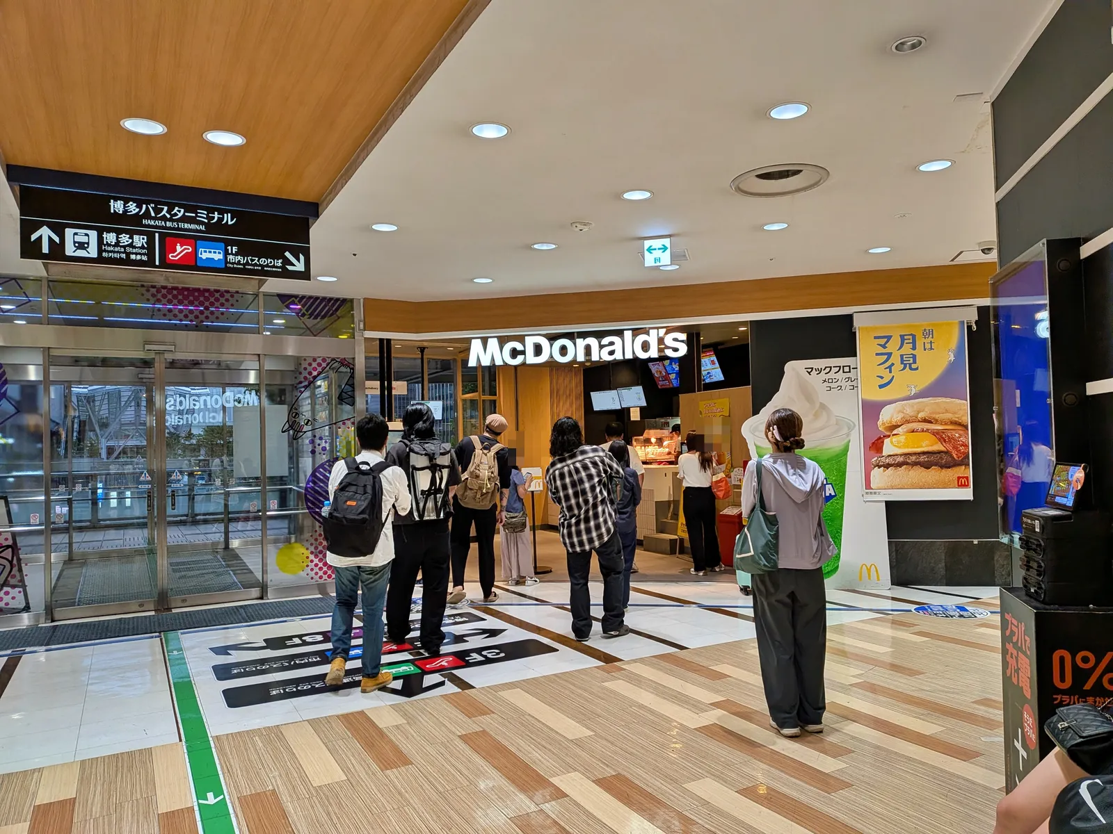 マクドナルド博多バスターミナル店。カウンター前に8人ほどの列。右に「朝は月見マフィン」のポスター