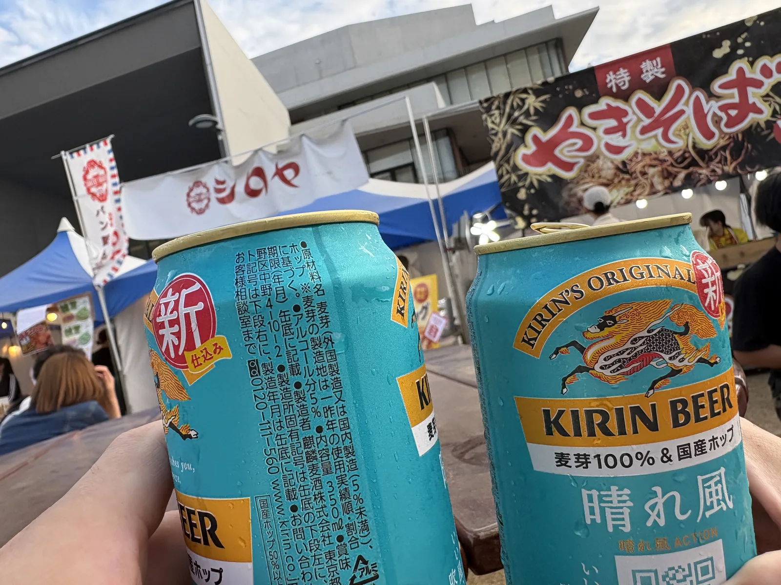 キリン晴れ風の缶2本で乾杯。奥にシロヤのテントとやきそばの屋台