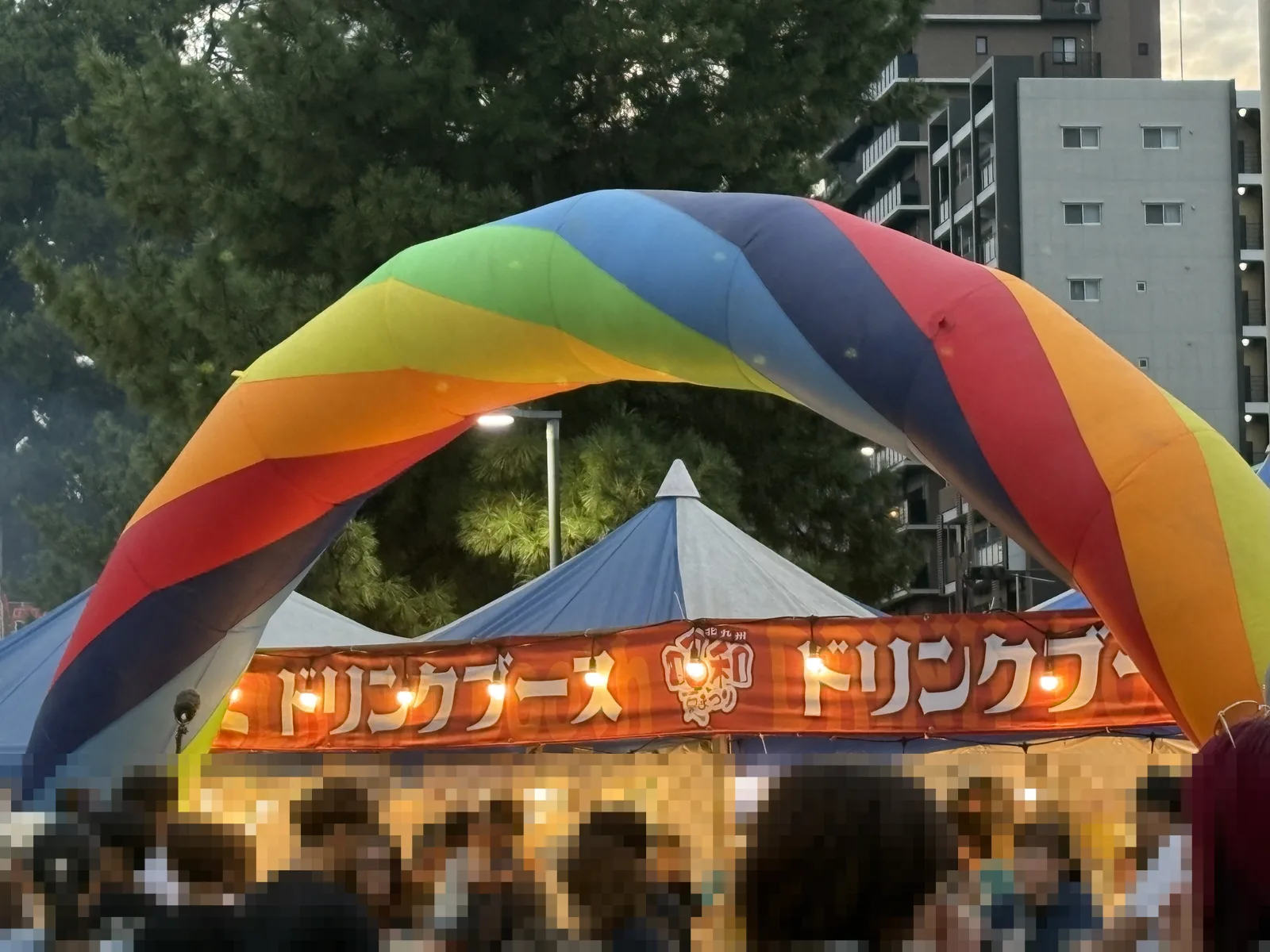 虹色のアーチの下にドリンクブースのテント。前に人だかり