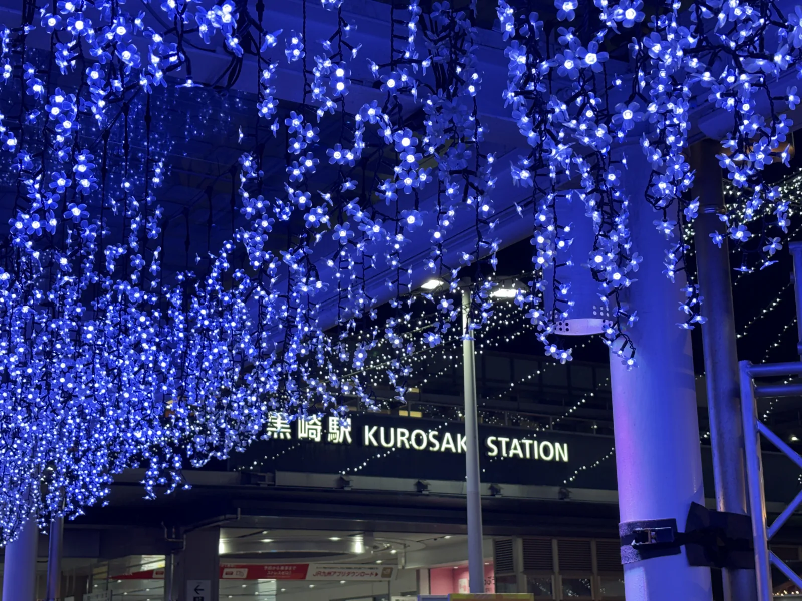 黒崎駅の駅名看板の前に、青いイルミネーションが垂れ下がる