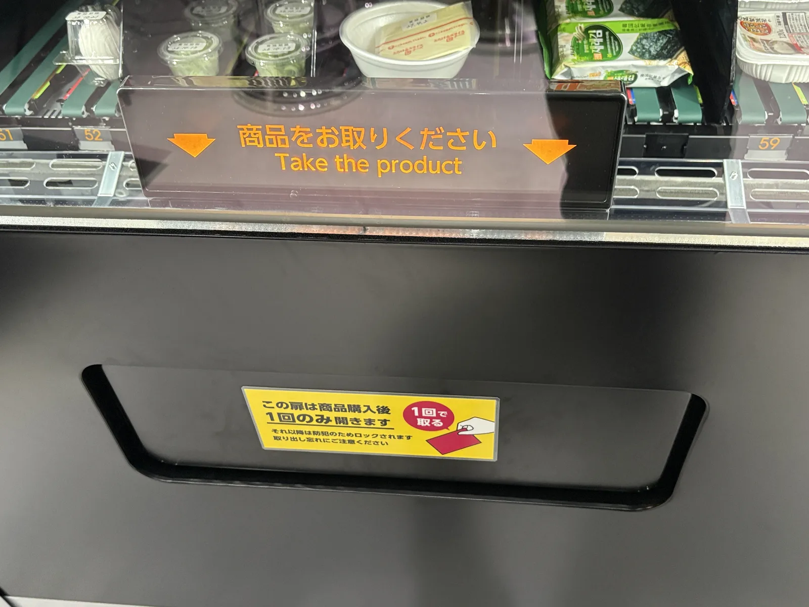 自販機のトッピングの段。たまご、カップ入りの具材、チーズ、のりが並ぶ。「この扉は商品購入後1回のみ開きます」の貼り紙