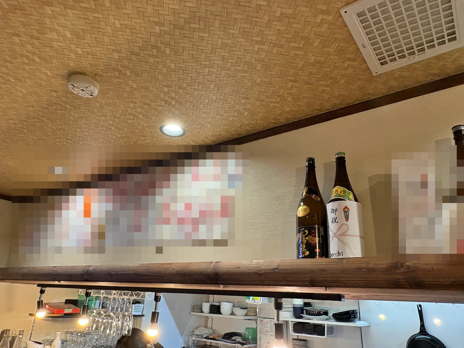 天井近くの壁に並ぶ開店祝いの祝儀袋と、棚の上の御祝のお酒(祝儀袋の名前はモザイク処理)