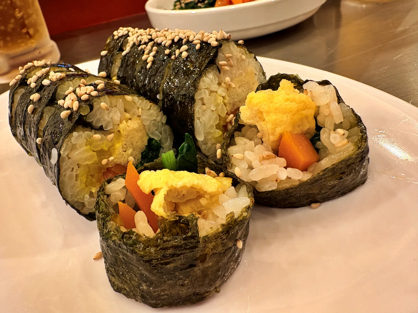 ごまをまぶしたキンパ。断面に玉子焼き、にんじん、ほうれん草、ねぎ