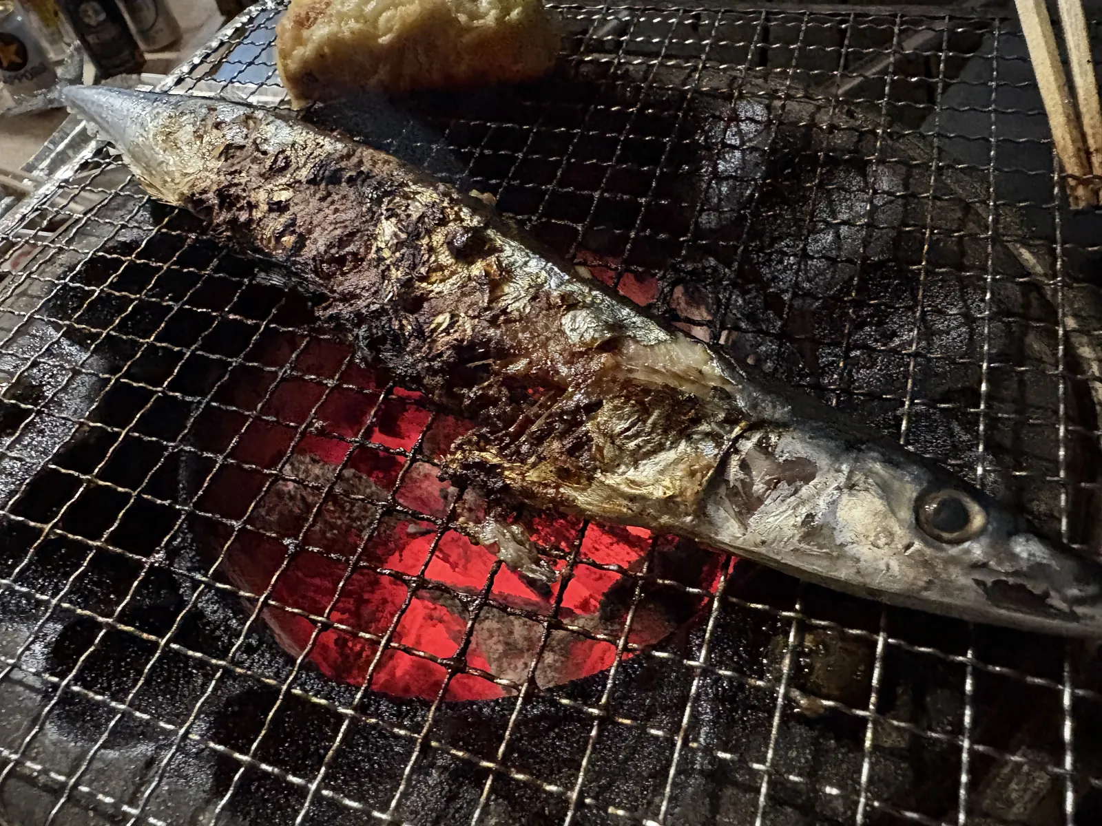 七輪の網の上で焼かれるサンマ。皮が焦げて香ばしそう