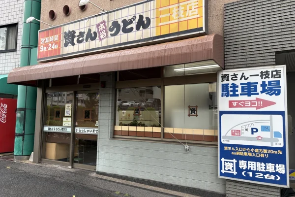 資さんうどん一枝店の外観。右に「資さん一枝店 駐車場 すぐヨコ!!」「専用駐車場（12台）」の看板