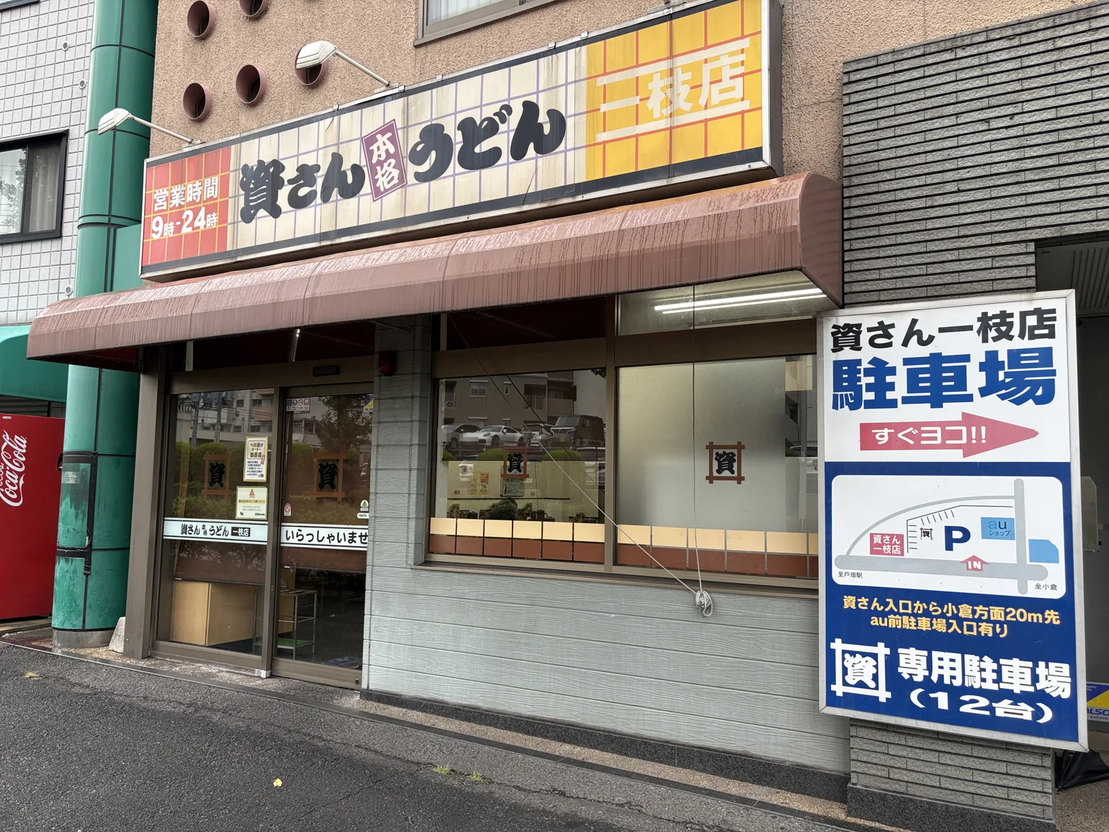 資さんうどん一枝店の外観。右に「資さん一枝店 駐車場 すぐヨコ!!」「専用駐車場（12台）」の看板