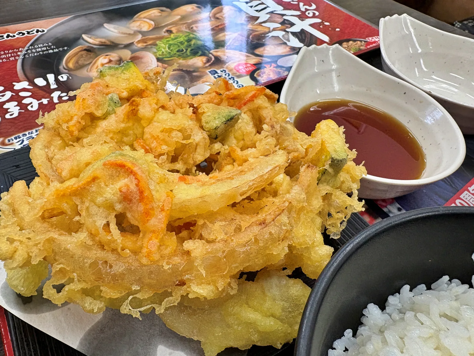 ジャンボ野菜かき揚げ天のアップ。タマネギ、人参、かぼちゃが衣でまとまっている。右に天つゆ