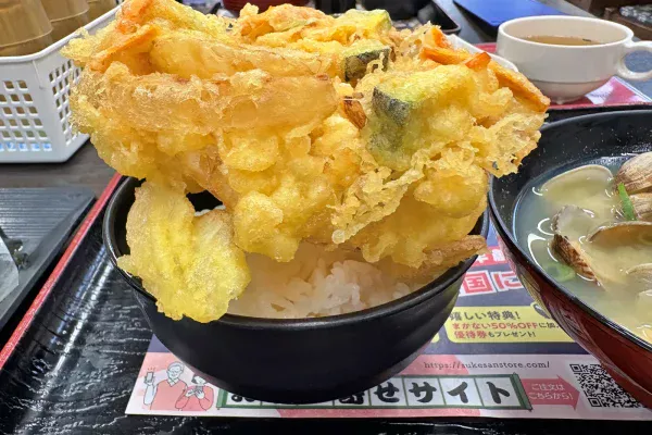 ごはんにのせたジャンボ野菜かき揚げ天を横から。かき揚げが茶碗から大きくはみ出している