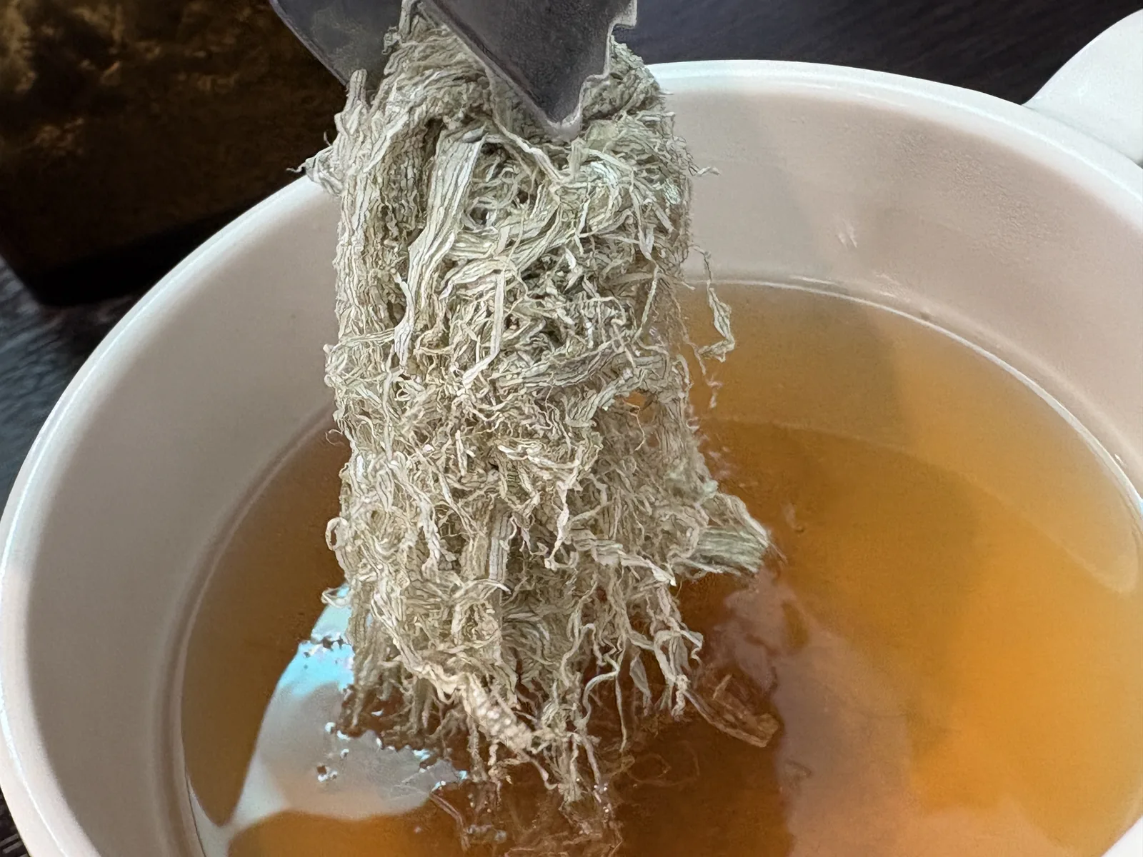 白い器のうどん出汁に、とろろ昆布をたっぷり入れているところ