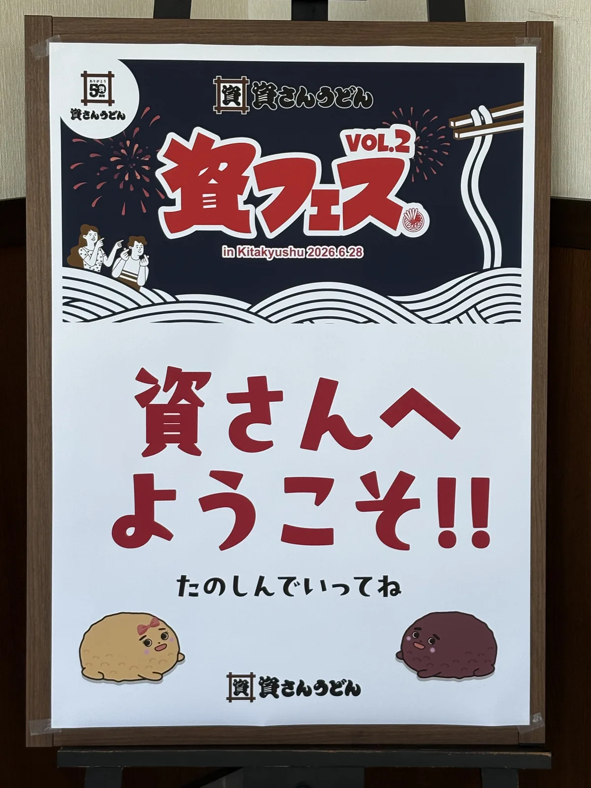 資フェスVol.2の看板。「資さんへようこそ!! たのしんでいってね」「in Kitakyushu 2026.6.28」