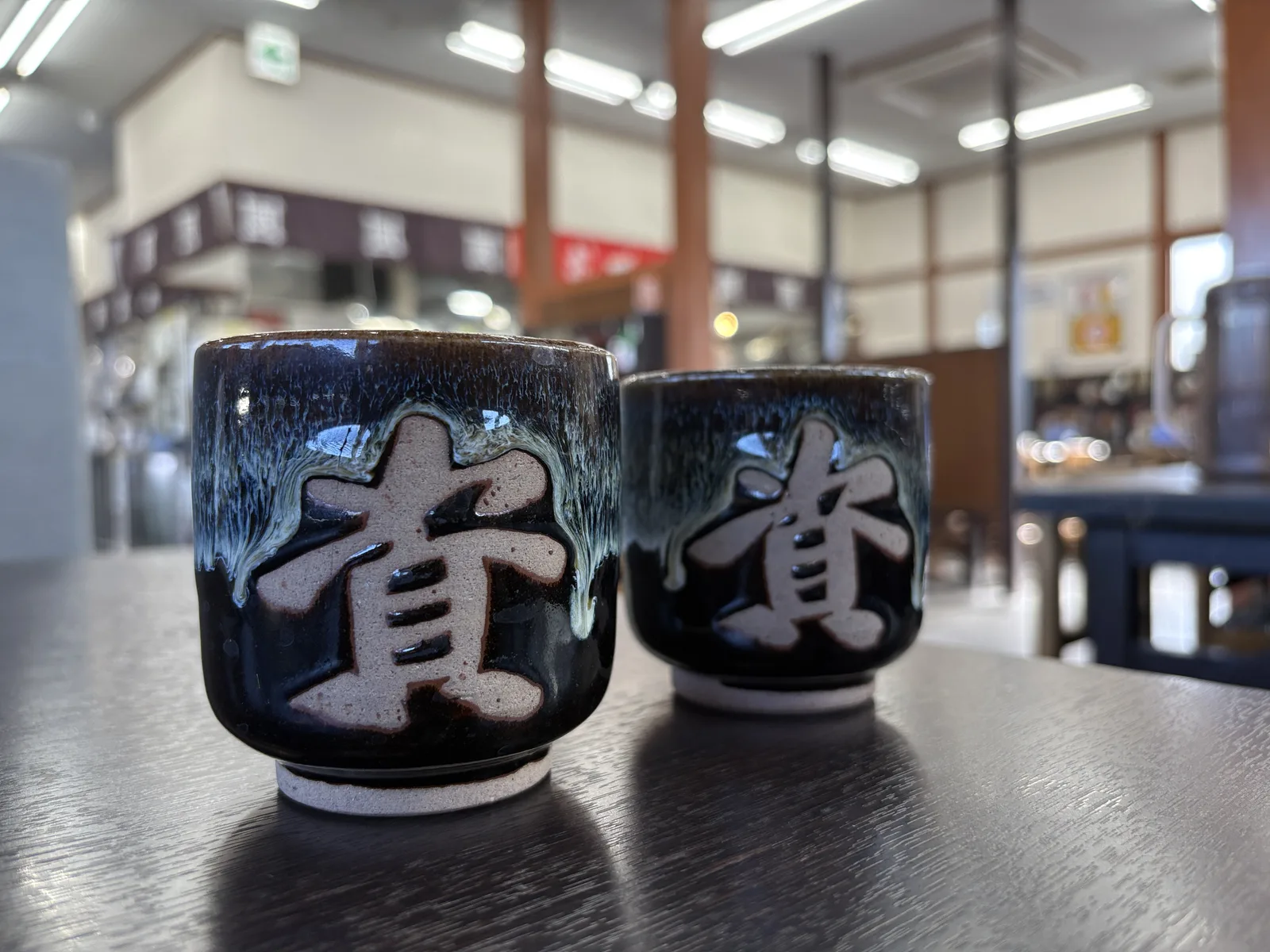 黒地に白い釉薬が垂れた、「資」の字入りの小石原焼きの湯飲み2つ