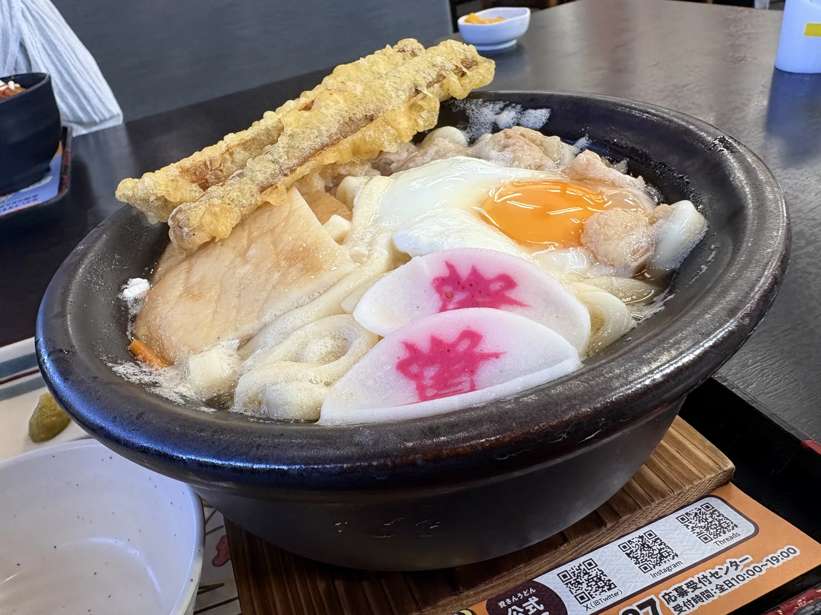 斜め横から見たもつ鍋うどん。土鍋の縁から湯気と泡が立つ