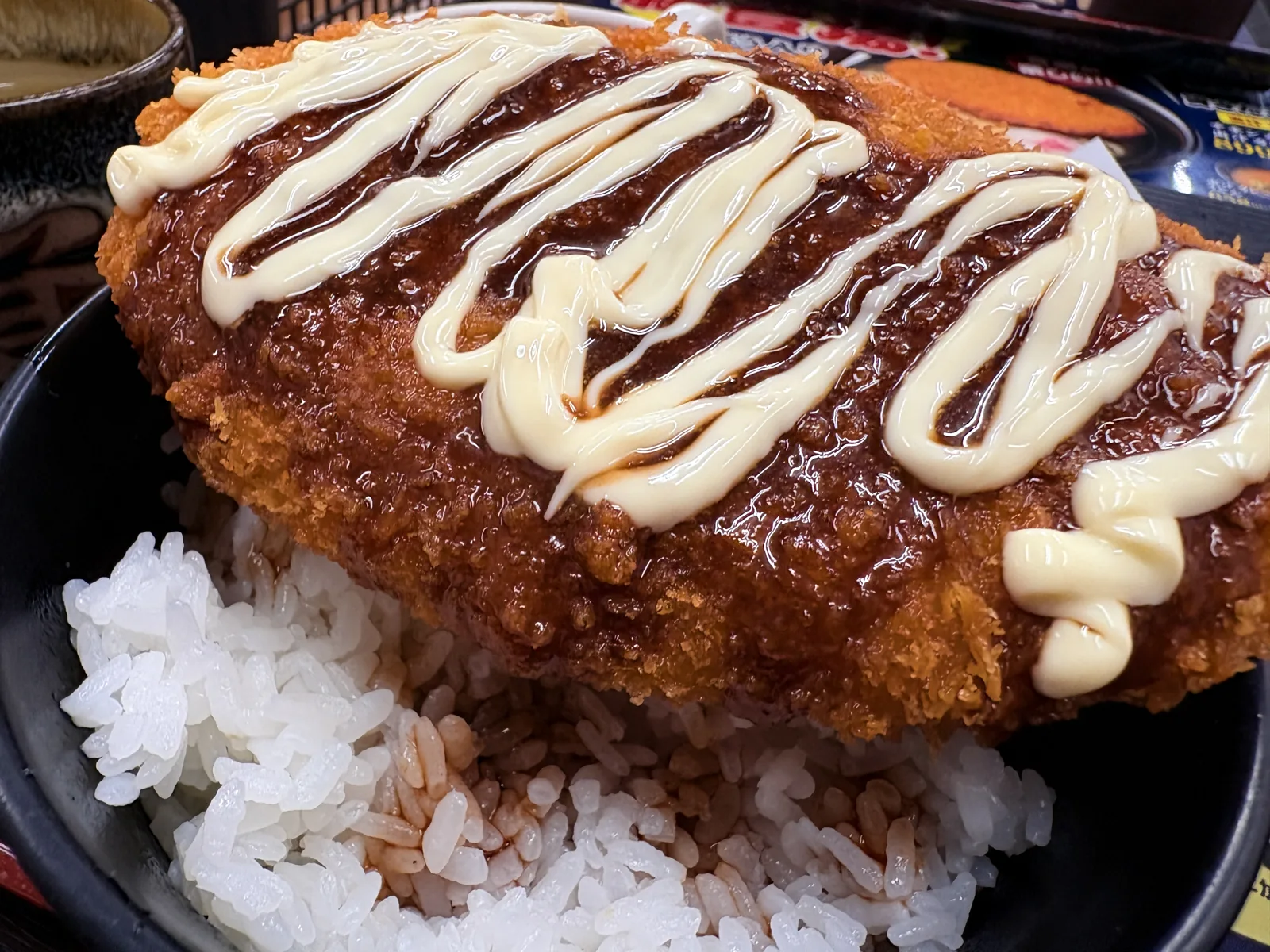 斜めから見たソースコロッケ丼。衣にソースがしみ込み、下のごはんにもソースが垂れている