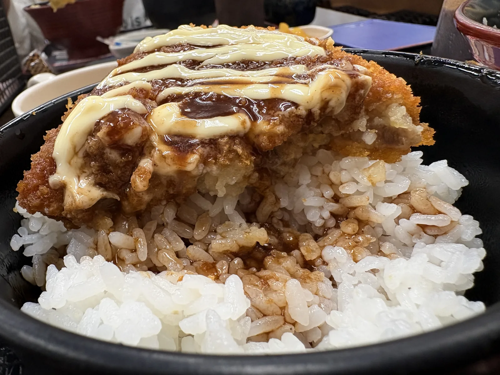 コロッケを半分ほど食べ進めたソースコロッケ丼。断面と、ソースのしみたごはん