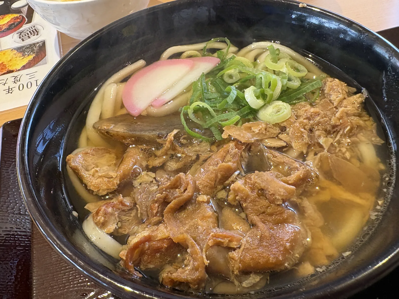 鶏皮うどん。黒い器に、甘辛く煮た鶏皮がびっしり
