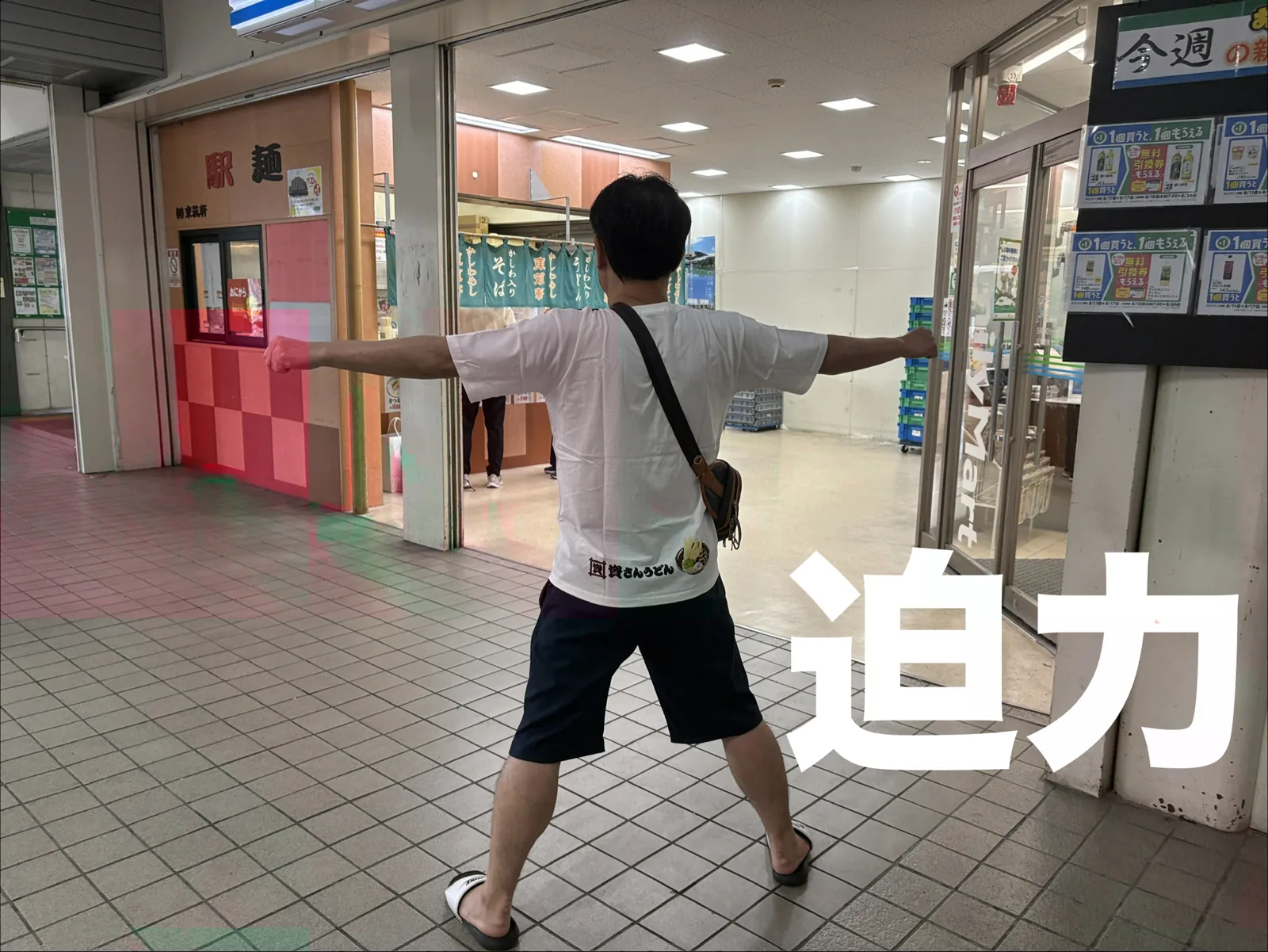赤間の店の前で迫力ポーズ。「駅麺」の看板がかかる駅の通路