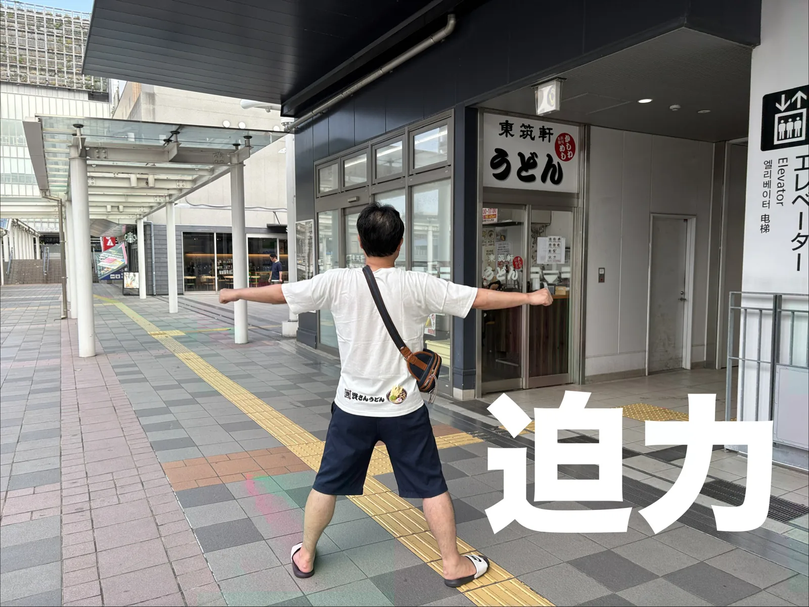 黒崎の店の前で迫力ポーズ。白い看板に「東筑軒 うどん」