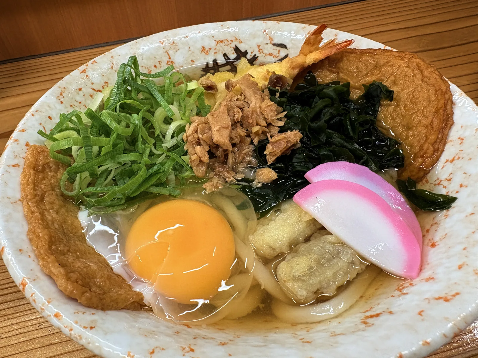 全部のせのうどん。丸天、きつね、海老天、わかめ、生卵、かしわ、ねぎがのって器からあふれそう