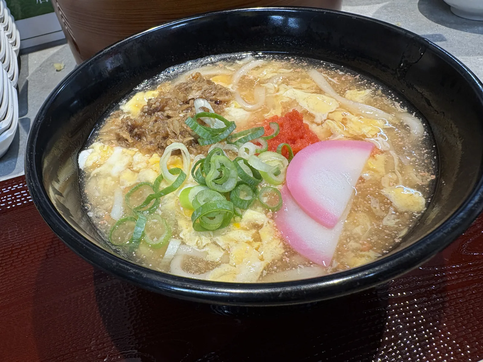 明太あんかけうどん。玉子とじのあんに明太子がのり、黒い器で出てくる