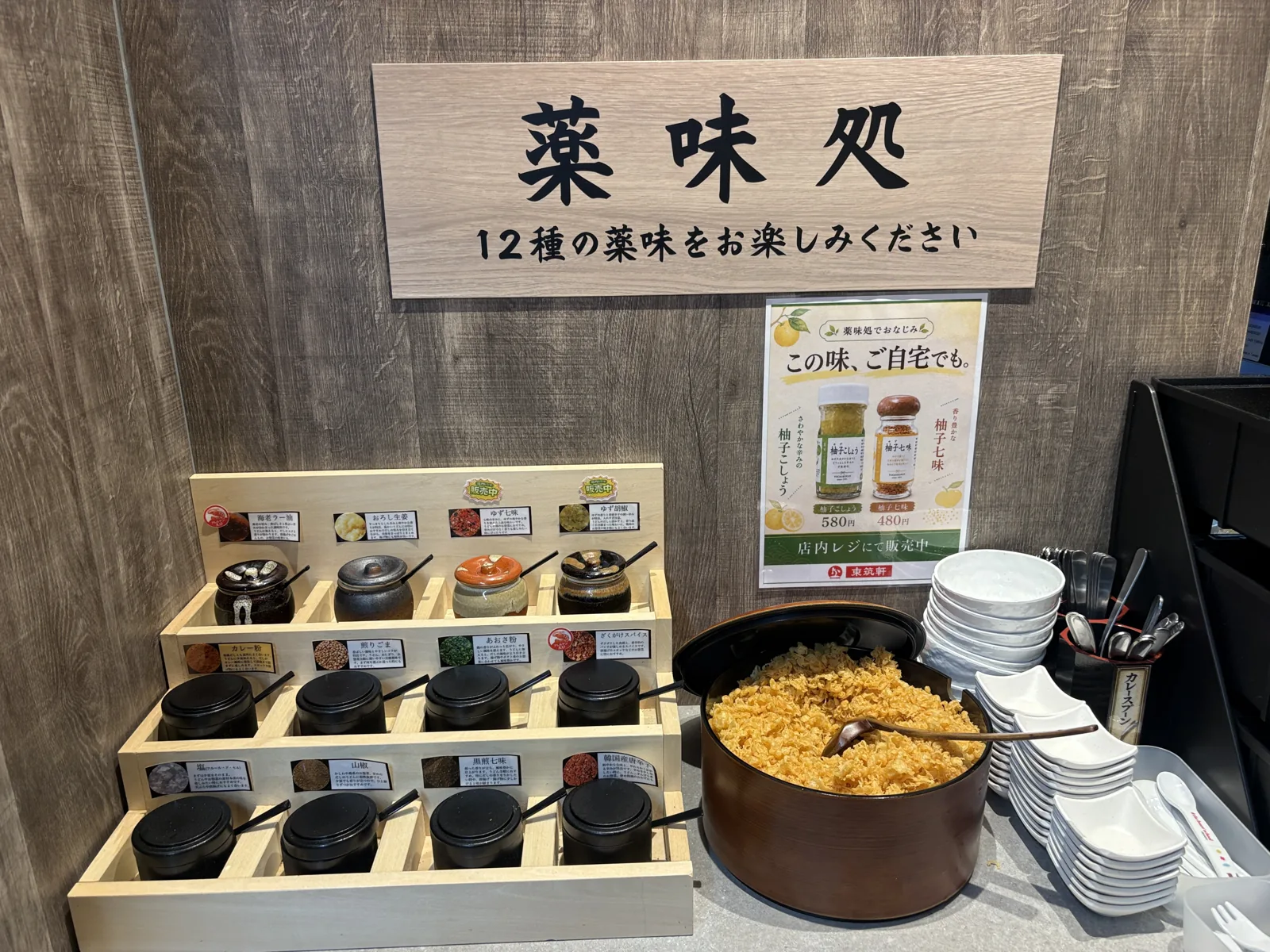 薬味処。「12種の薬味をお楽しみください」の看板の下に薬味の壺が並び、右に天かすの器