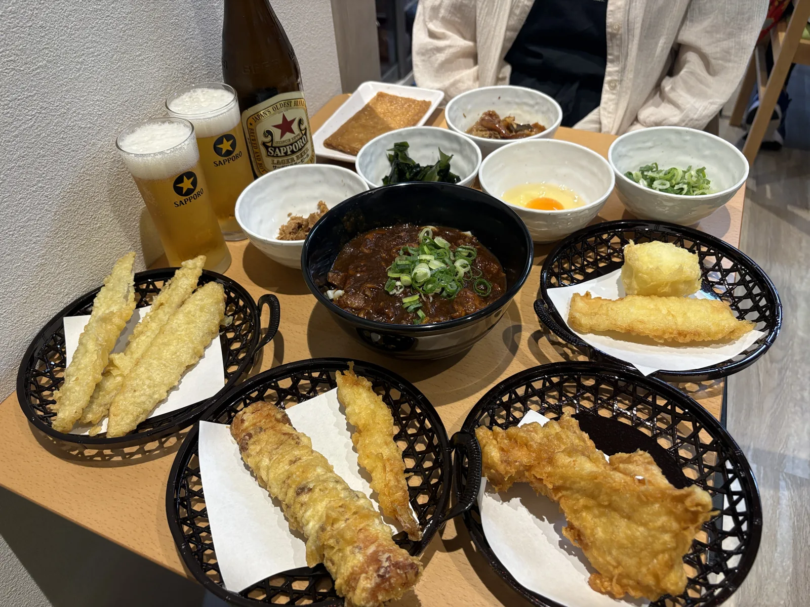 角度を変えて見たテーブル。手前に天ぷらのかご3つ、奥に小鉢が並ぶ。向かいに嫁
