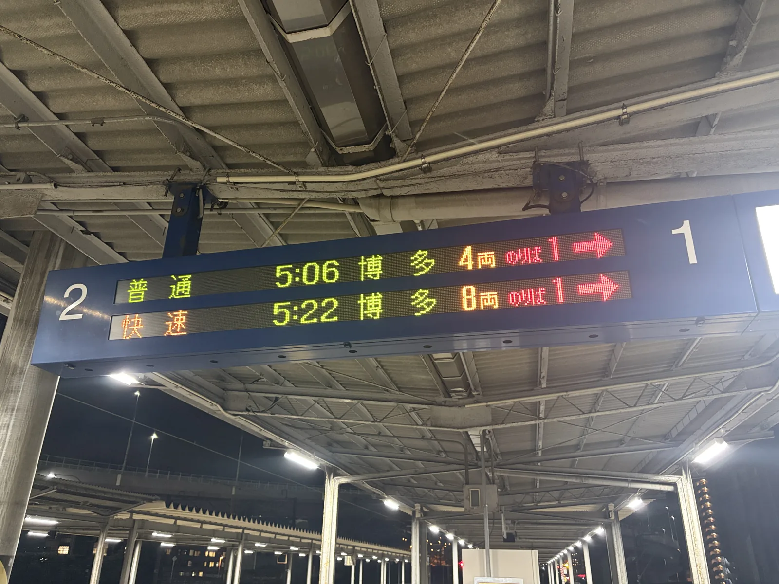 まだ暗いホームの発車案内。「普通 5:06 博多 4両」「快速 5:22 博多 8両」