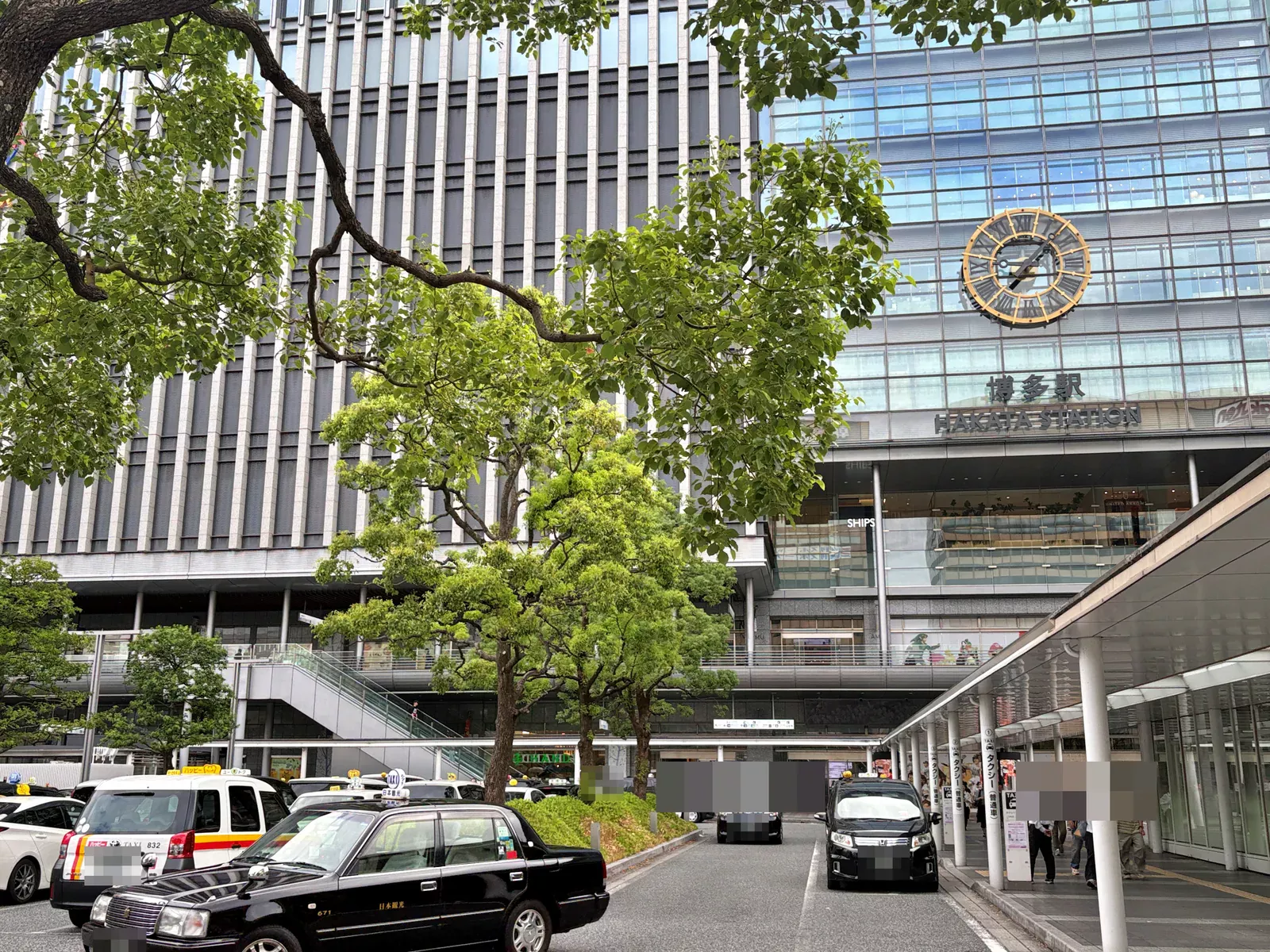博多駅の駅舎。大時計と「博多駅 HAKATA STATION」の文字、手前にタクシー乗り場と街路樹