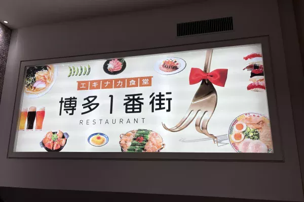 博多1番街の看板。「エキナカ食堂 博多1番街 RESTAURANT」の文字と、もつ鍋・ラーメン・寿司などの料理写真