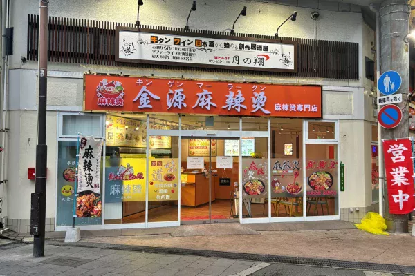 金源麻辣湯の外観。オレンジの看板に「金源麻辣湯（キンゲンマーラータン）麻辣湯専門店」、店先に「営業中」ののぼり