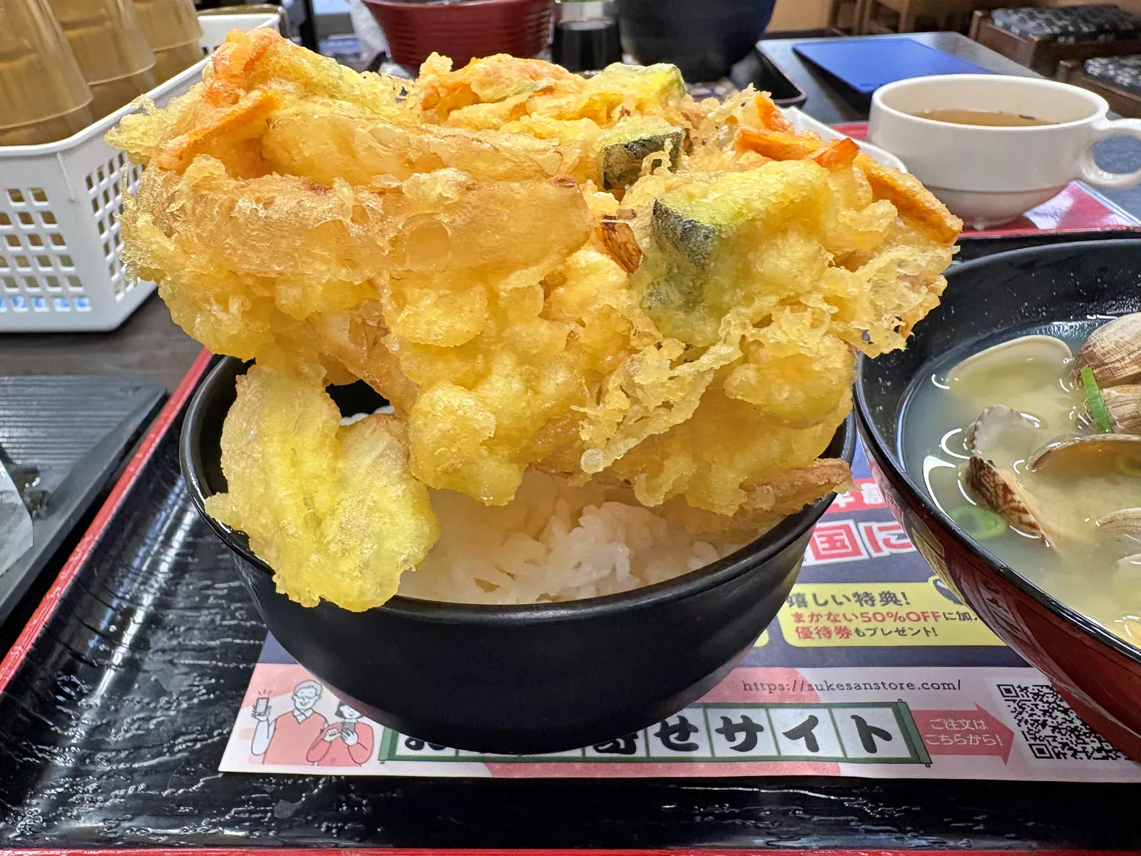 ごはんにのせたジャンボ野菜かき揚げ天を横から。かき揚げが茶碗から大きくはみ出している