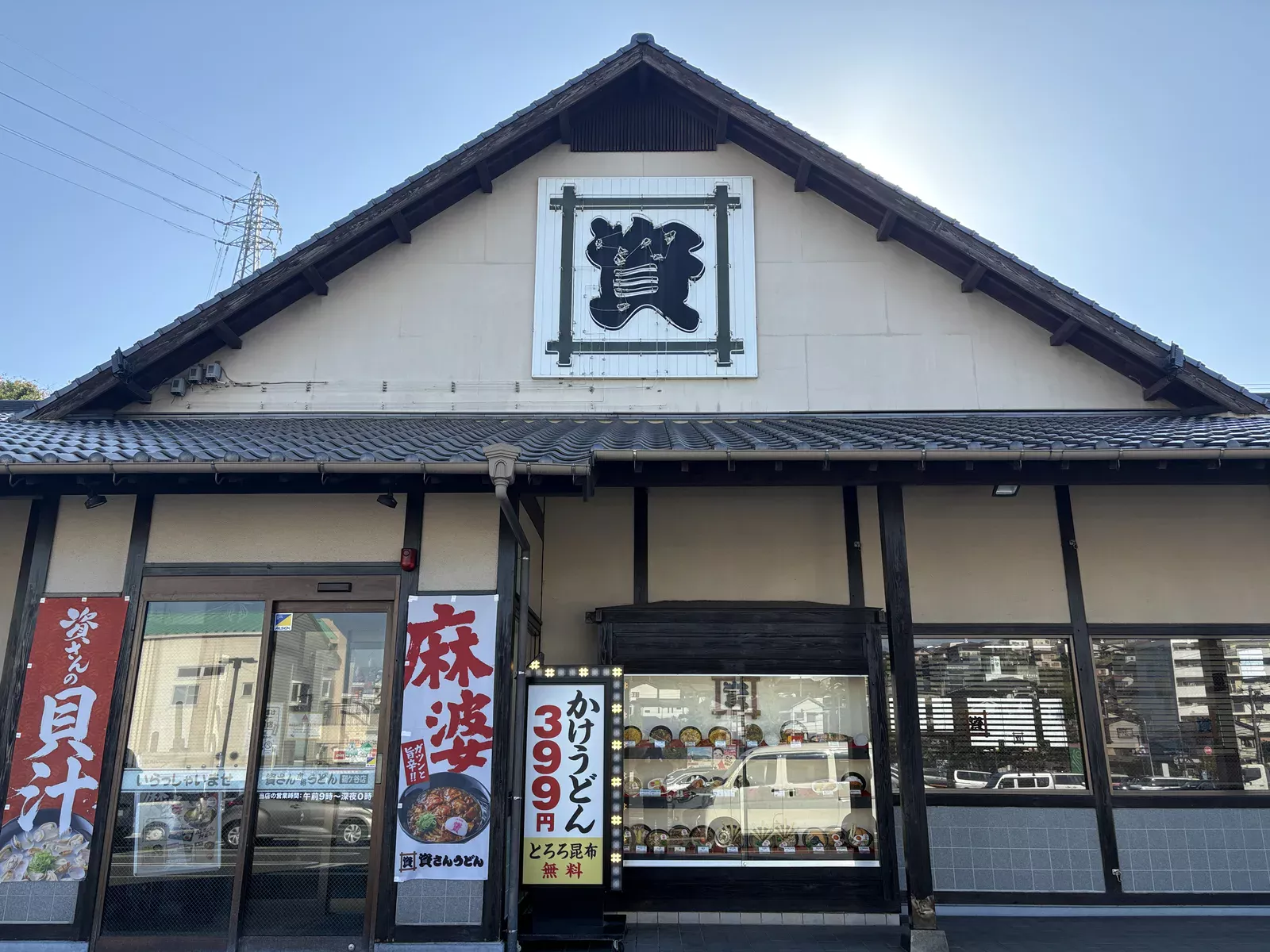 資さんうどん鞘ヶ谷店の外観。瓦屋根の破風に「資」の看板、のぼり「資さんの貝汁」「麻婆」と電飾看板
