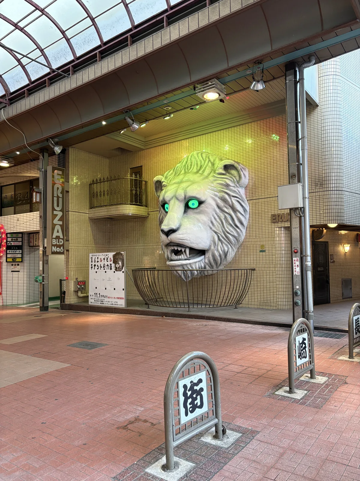 ビルの壁から突き出たライオンの頭のオブジェ。目が緑に光っている