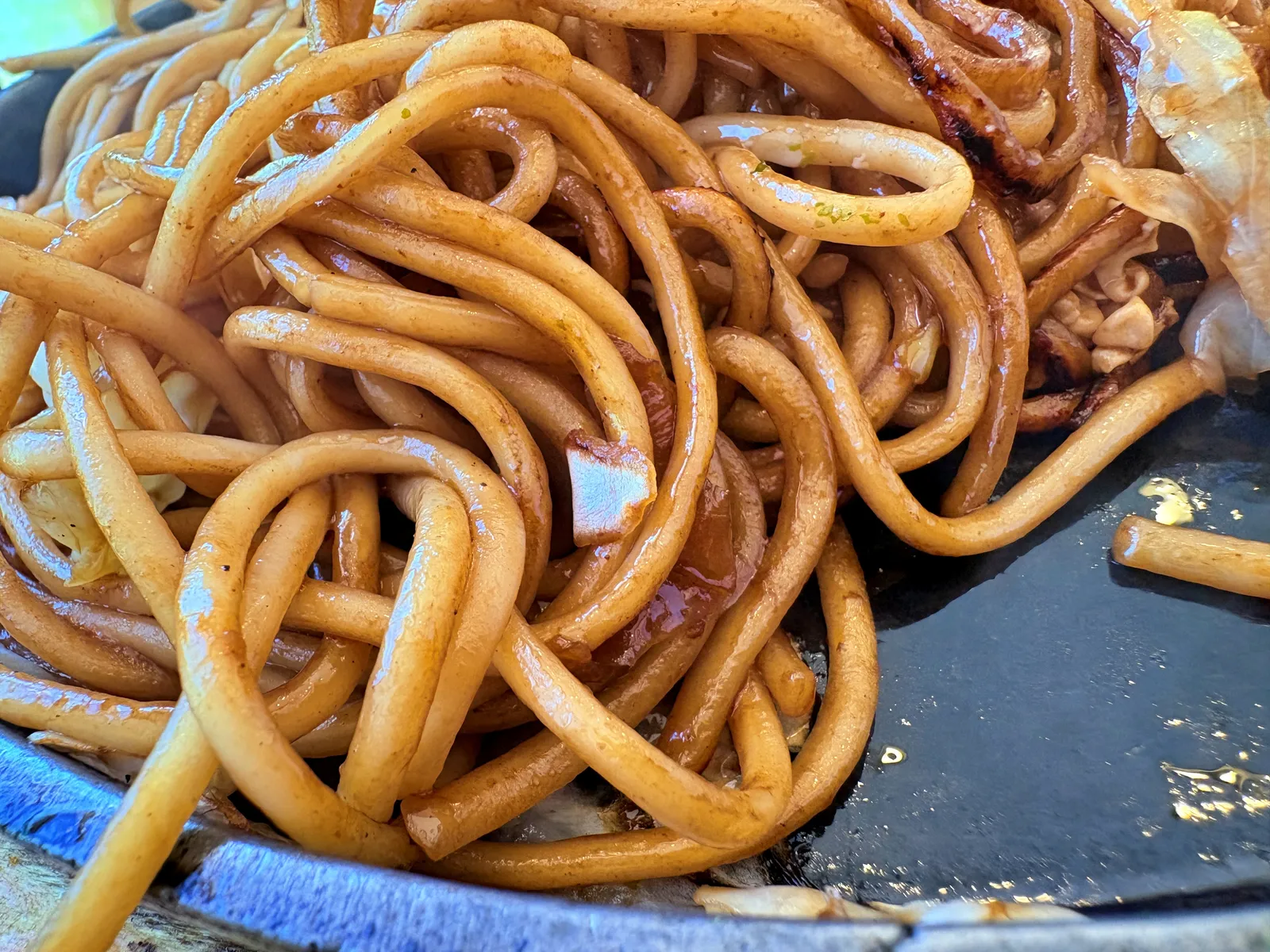 鉄皿の上の焼そばの麺のアップ。タレがからんでツヤツヤ